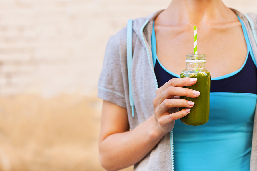 Woman drinking vegetable smoothie after fitness running workout